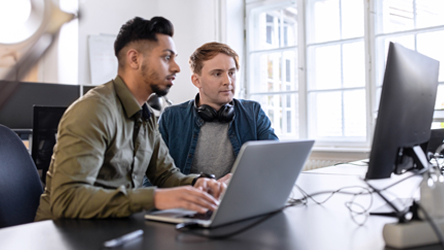 IT stručnjaci u modernoj kancelariji rade na računarima, fokusirani na analizu podataka i razvoj tehnoloških rešenja.