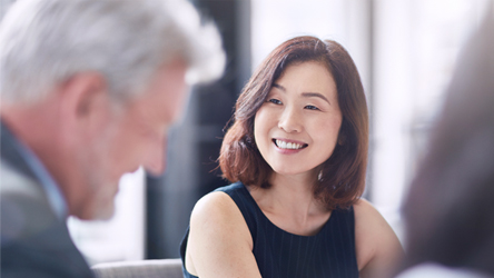 Poslovni sastanak sa nasmejanim kolegama u profesionalnom okruženju, simbolizujući timski rad i podršku.