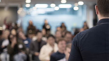 Grupa zaposlenih na sastanku u dinamičnom poslovnom okruženju, diskutuje i razmenjuje ideje.