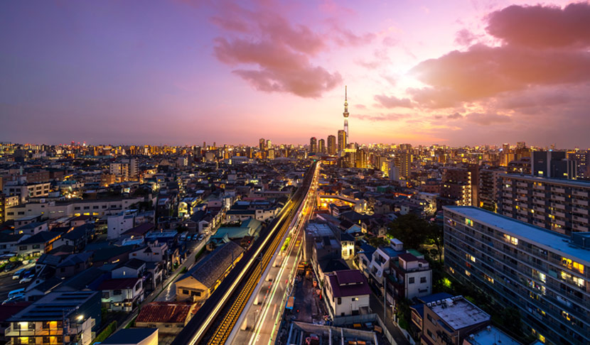 Panoramski pogled na grad pri zalasku sunca, sa osvetljenim ulicama i urbanim pejzažom koji simbolizuje povezanost i raznolikost.