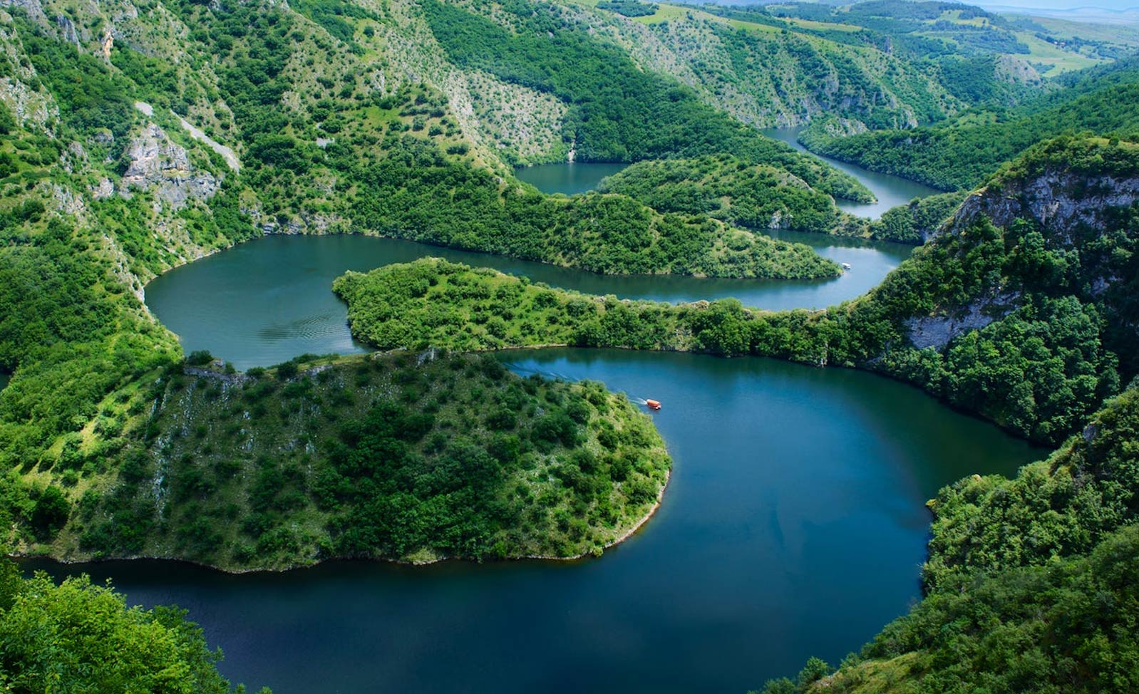 Prelep pejzaž reke koja vijuga kroz zelene planine, prikazuje netaknutu prirodu Srbije.