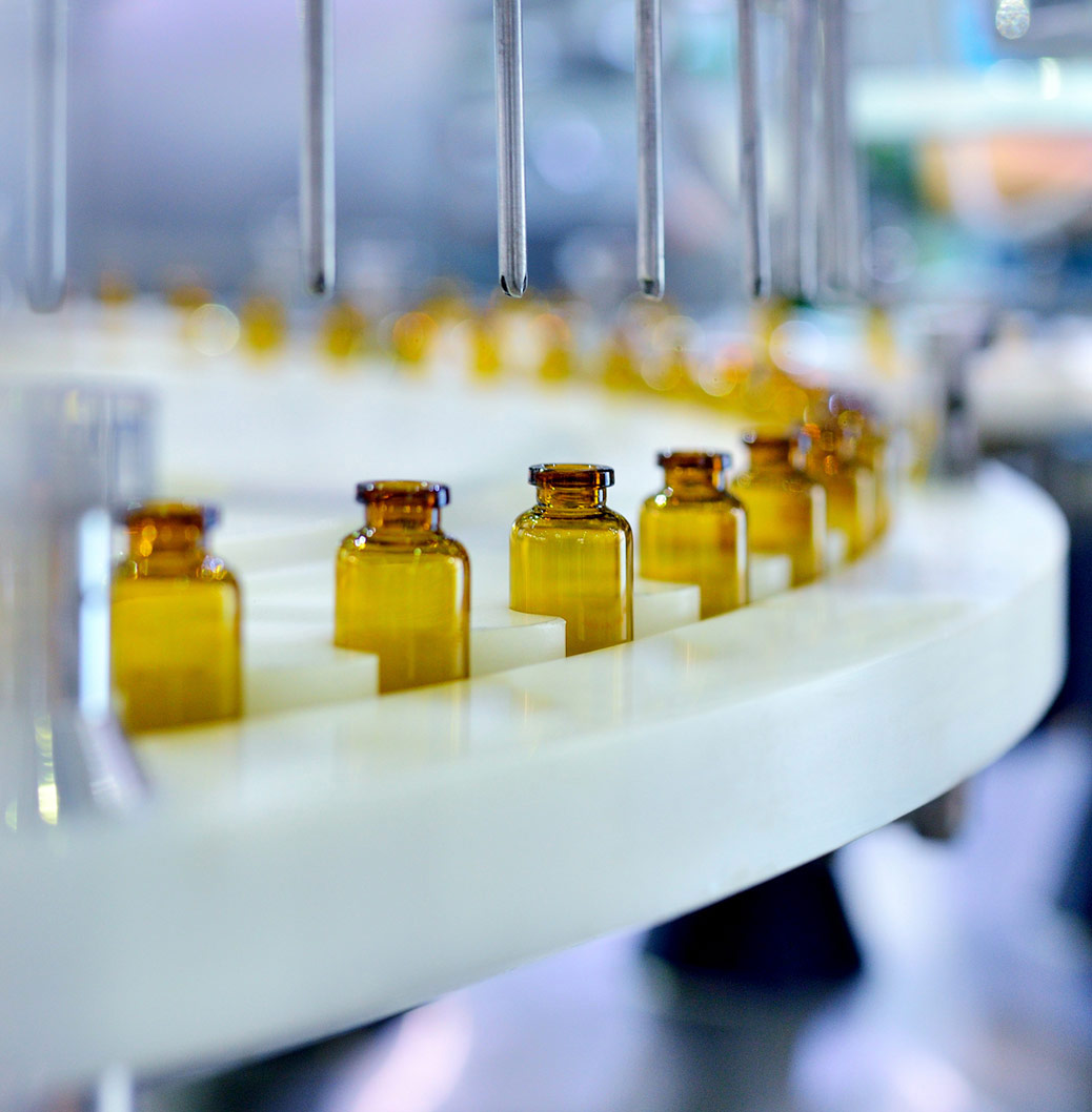 Proizvodna linija u farmaceutskoj fabrici sa nizom malih staklenih bočica koje se kreću po traci, spremne za punjenje ili zatvaranje.
